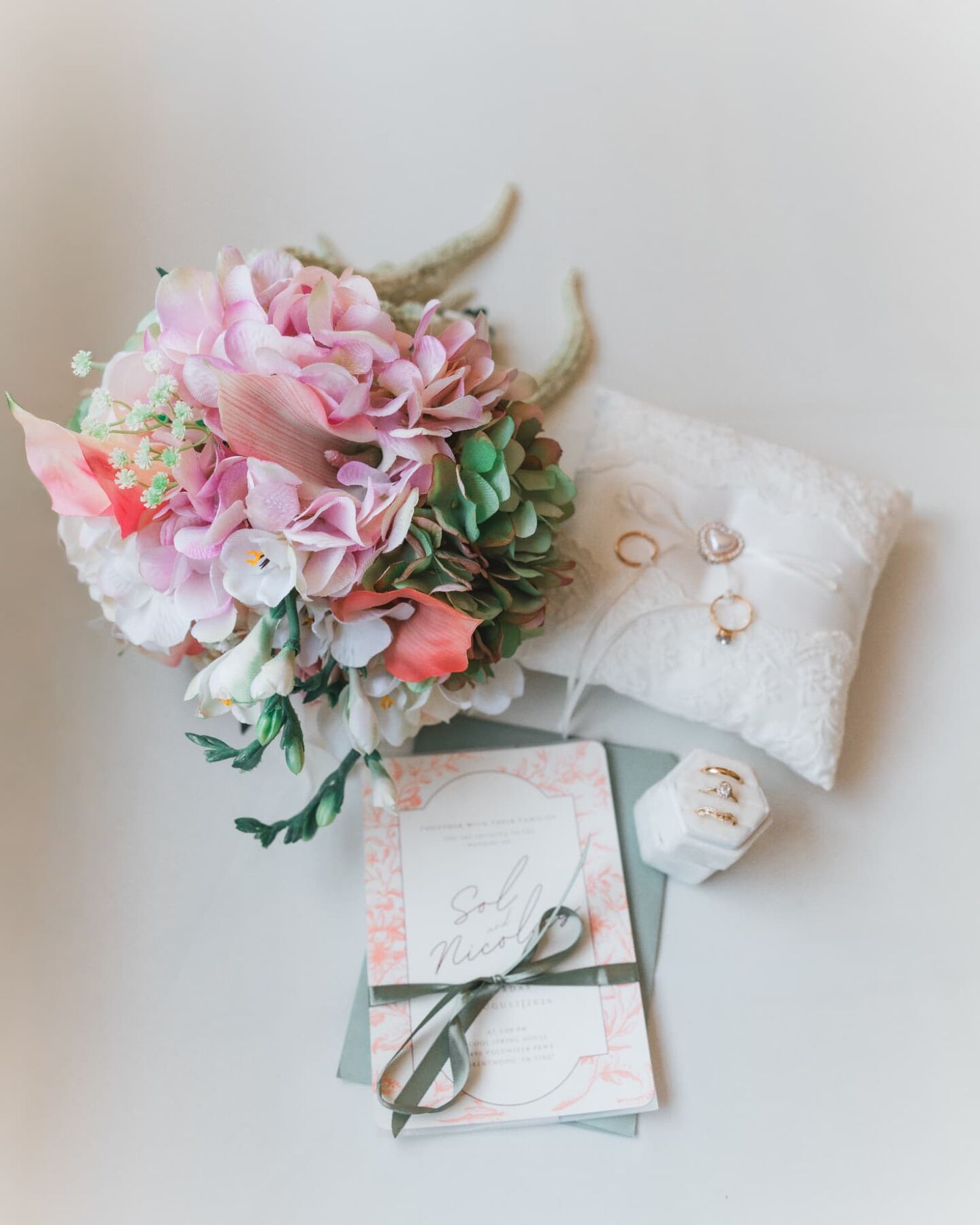 Wedding day flat lay with bouquet, rings and invitation suite