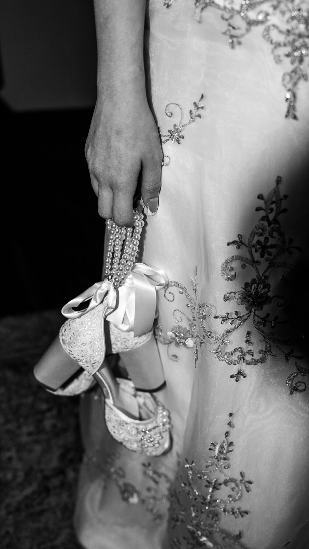 Black and white detail of bridal shoes and a beaded wedding gown
