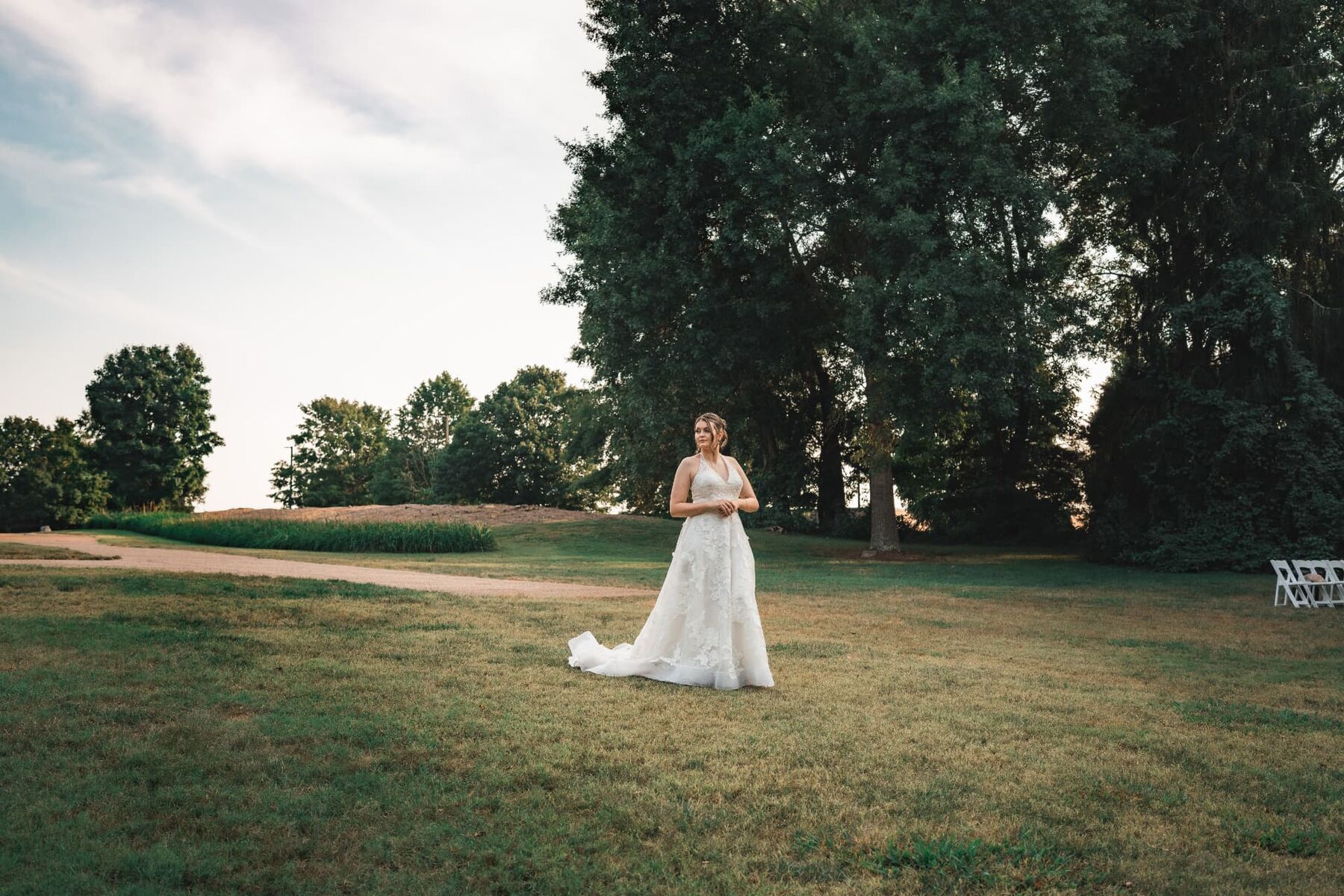 Bride standing in an open lawn at sunset before her ceremony